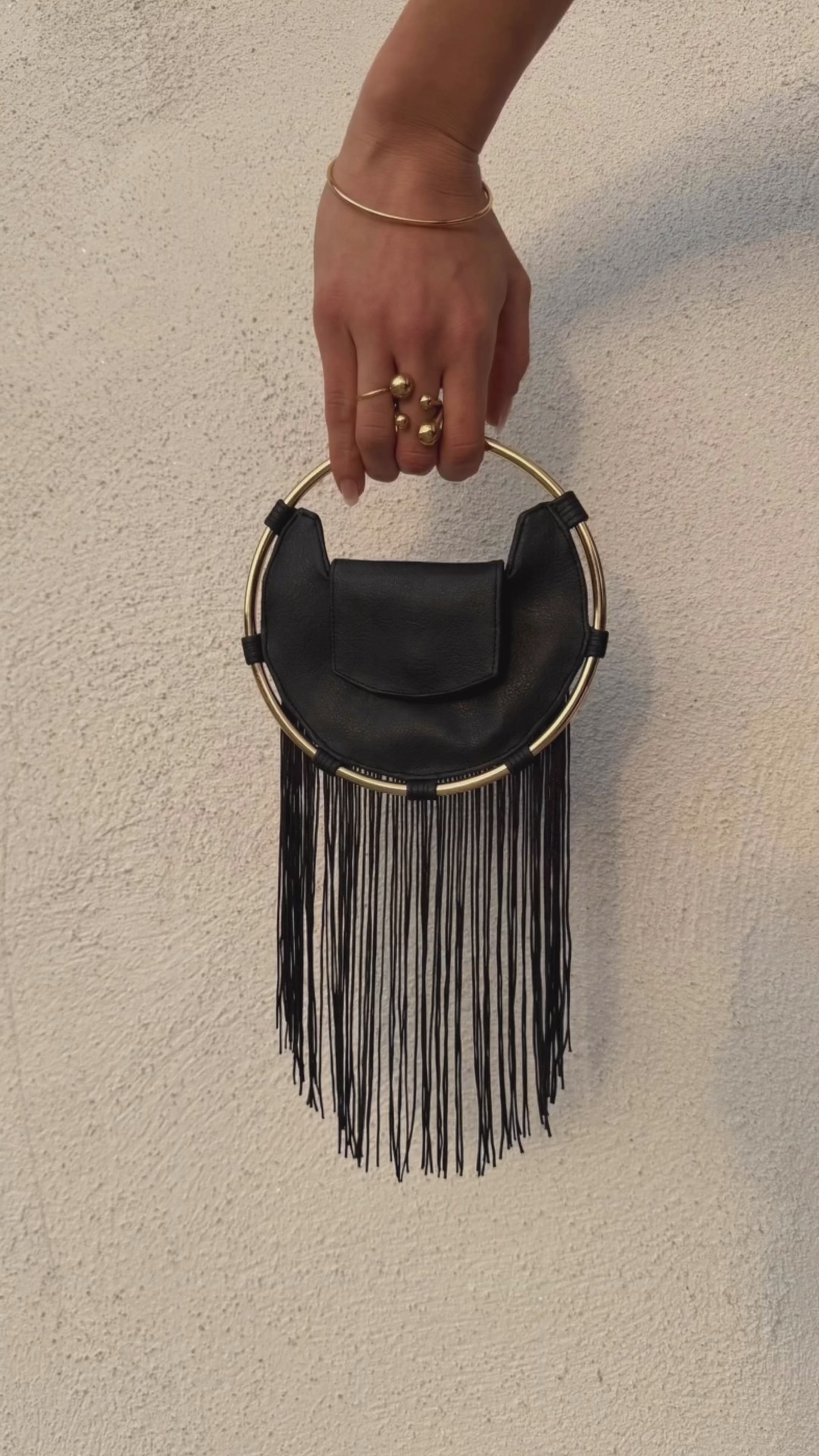 A sculptural handbag handcrafted in France from full-grain leather. Defined by its iconic circular gold ring and long leather fringes, made in limited pre-order editions.
